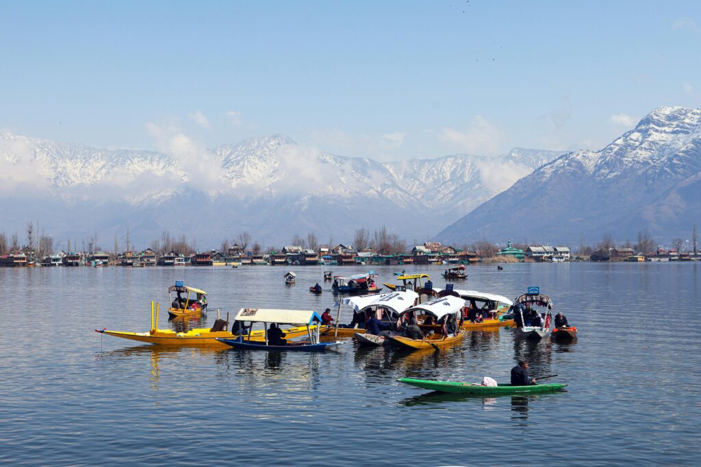 Beautiful scene of Dal Lake in Srinagar with colorful shikaras and snow-capped mountains in the background.