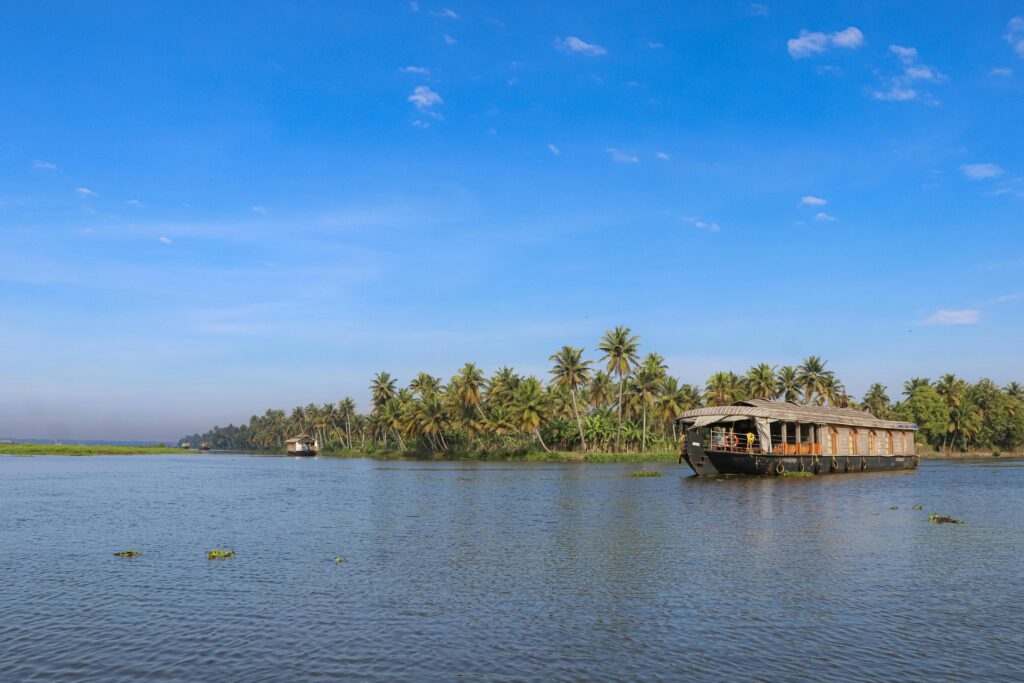 Tranquil scene of a houseboat on serene backwaters surrounded by lush greenery in Kumarakom, Kerala.