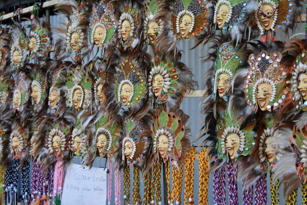 A vibrant collection of ornate carnival masks with feathers and jewels on display.